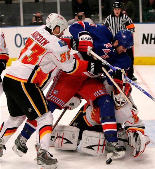 The Flames' goalie Miikka Kiprusoff, right, and teammate Adrian Aucoin, left, fight with the Rangers' Aaron Voros for the puck